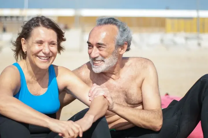 Smiling mature couple sitting together on a sunny coastal beach