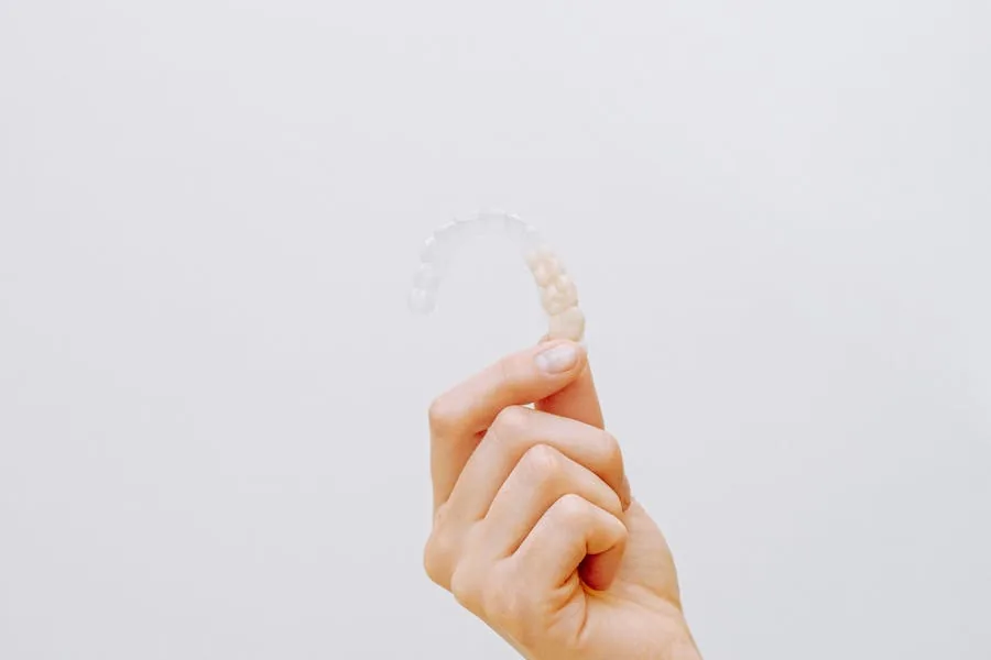 Adult woman holding a clear Invisalign aligner tray