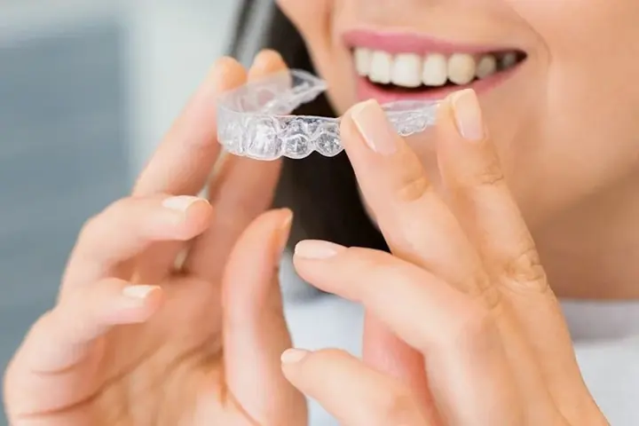 Woman holding a clear Invisalign aligner tray