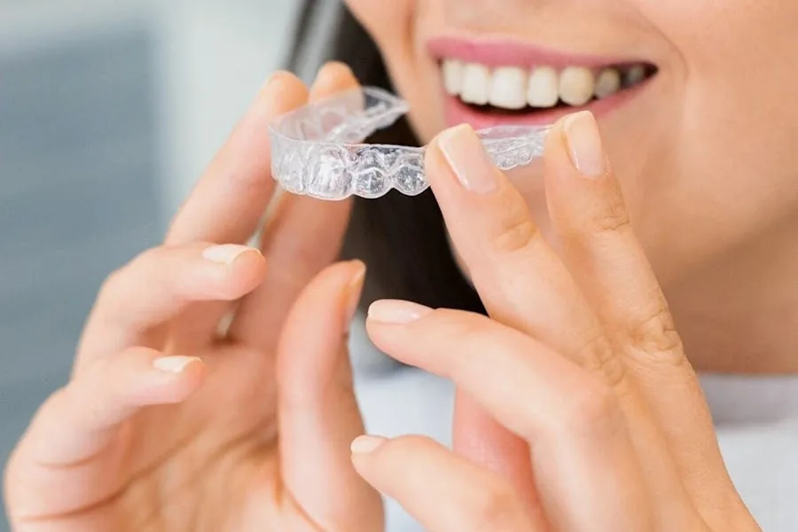 Woman holding a clear Invisalign aligner tray